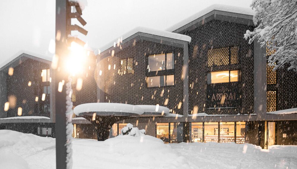 Amrai Suites Hotel im Montafon Außenansicht im Winter mit Schneefall und Schnee auf der Straße und Dächern